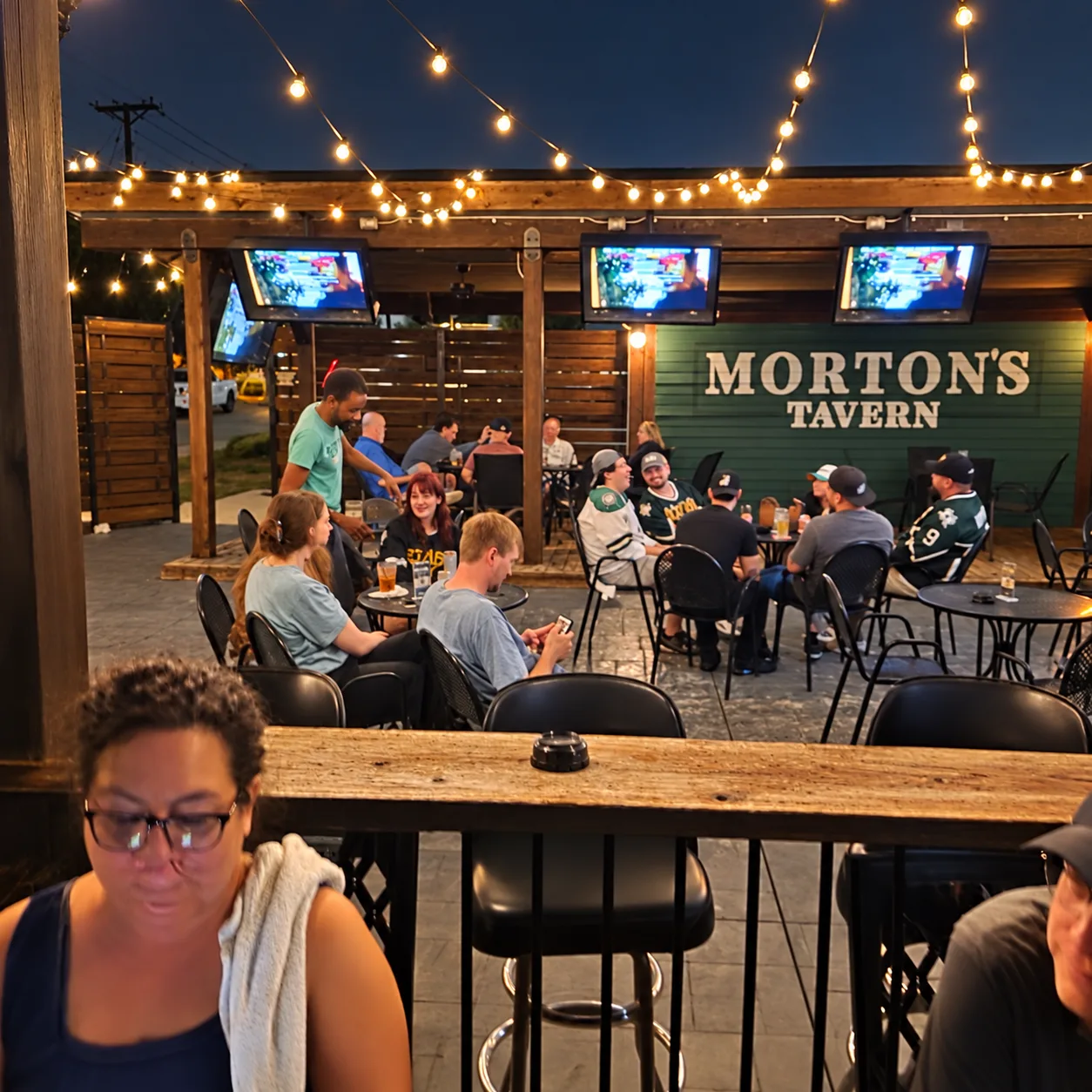 Friends hanging out on the string-lit patio at night at Morton's Tavern in Fort Worth